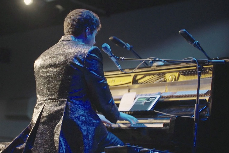 Jeremy Dutcher plays a piano with 3 microphones in front of him